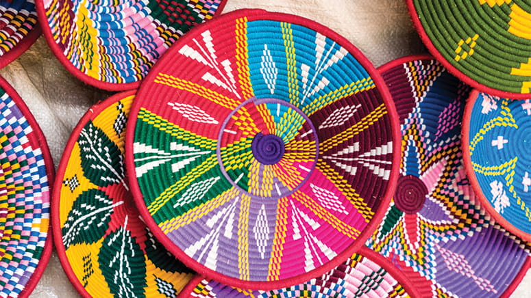 Colorful woven baskets sit in a pile.